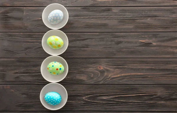 Skålar med färgglad påsk ägg på trä bakgrund — Stockfoto