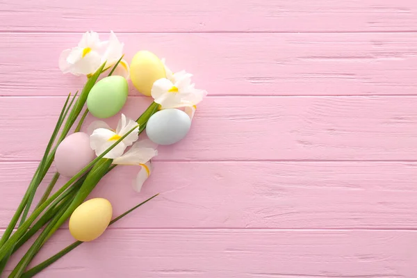 Uova di Pasqua con fiori primaverili su sfondo di legno a colori — Foto Stock