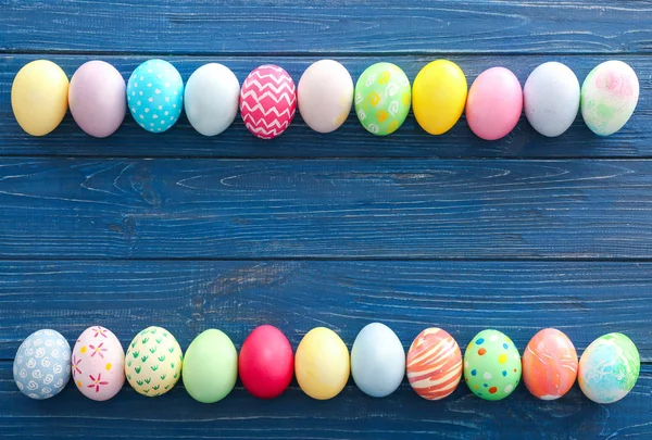 Barevná velikonoční vejce na dřevěném pozadí, horní pohled — Stock fotografie