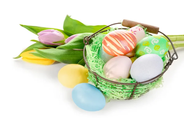 Великодній кошик з різнокольоровими яйцями і букетом квітів на білому тлі — стокове фото