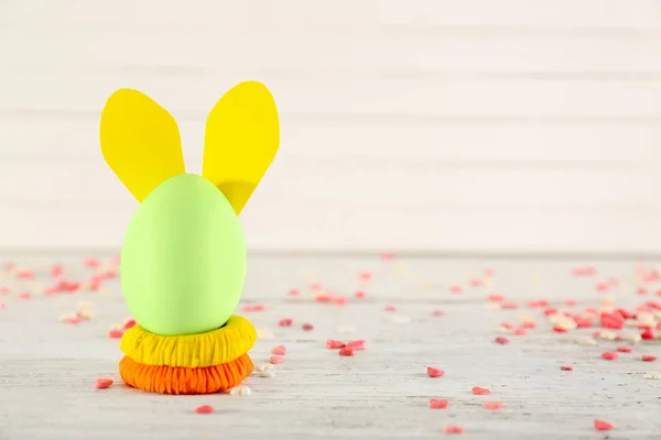 Easter egg decorated with bunny ears on light table — Stock Photo, Image