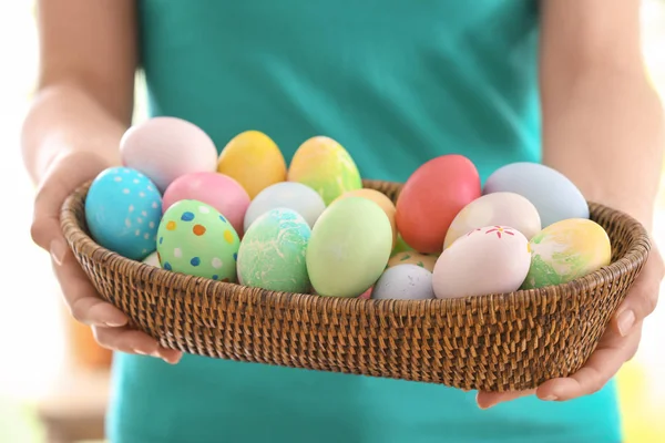 Young woman with wicker bowl full of colorful Easter eggs, closeup — Stock Photo, Image