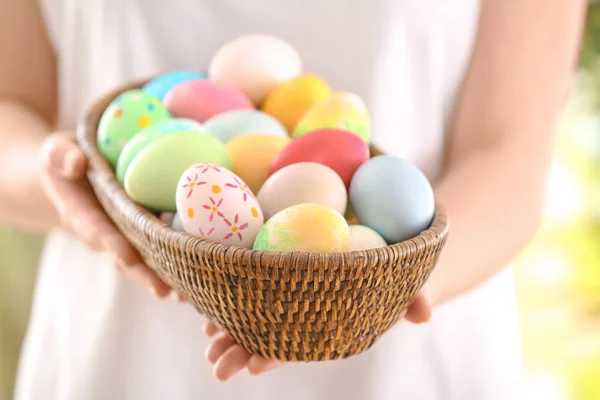 Young woman with wicker bowl full of colorful Easter eggs, closeup — Stock Photo, Image