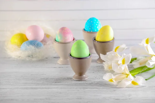 Чашки с пасхальными яйцами на светлом столе — стоковое фото