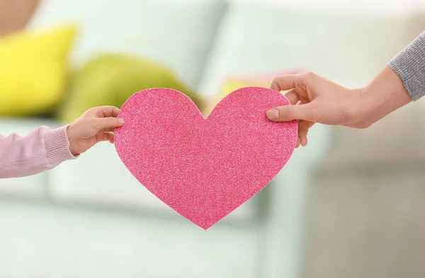Girl and her mother holding paper heart on blurred background — Stock Photo, Image