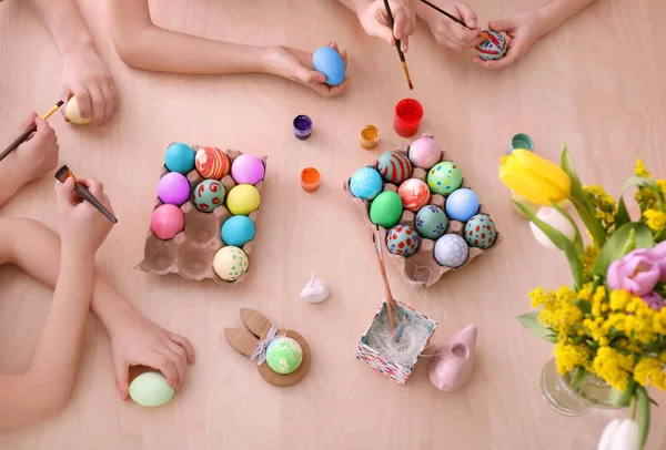 Cute little children painting eggs for Easter at table — Stock Photo, Image