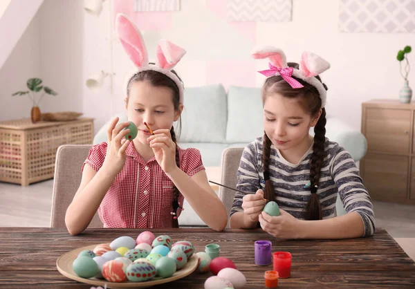 Meninas bonitos pintando ovos para a Páscoa à mesa — Fotografia de Stock