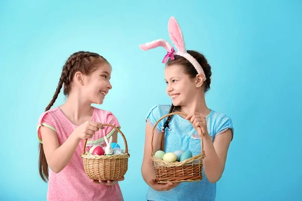 Hasır sepetleri ile Paskalya yumurtaları renkli arka plan üzerinde tutarak sevimli küçük kız — Stok fotoğraf