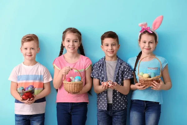 Niedliche kleine Kinder mit Ostereiern auf farbigem Hintergrund — Stockfoto