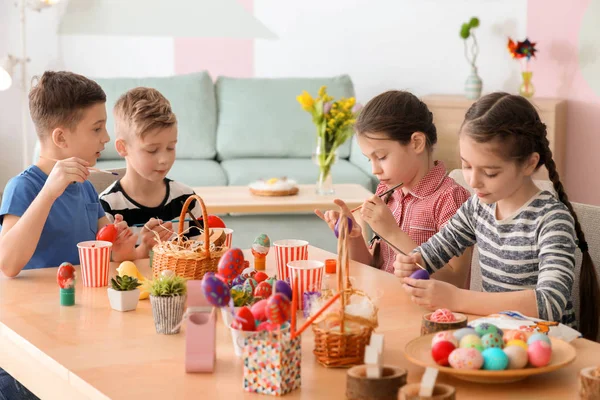 Cute little children painting eggs for Easter at table — Stock Photo, Image