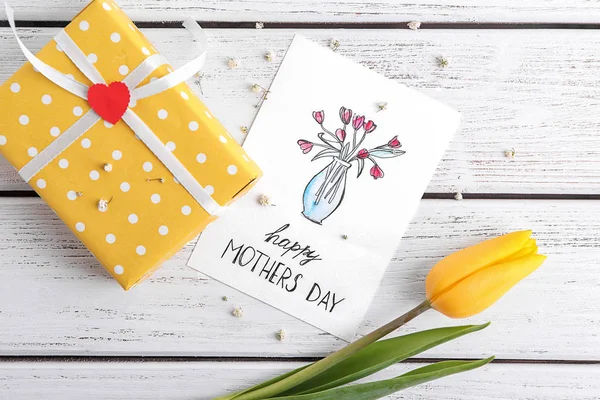 Greeting card with phrase "Happy  Mother's day" and gift box on table — Stock Photo, Image