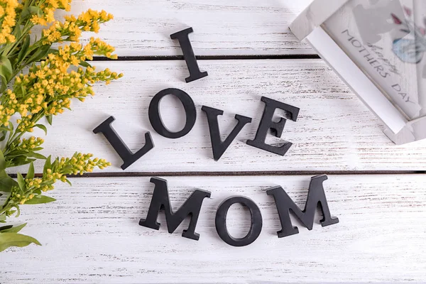 Frase "Amo a mamá" hecha de letras sobre fondo de madera. Saludo para el día de la madre —  Fotos de Stock