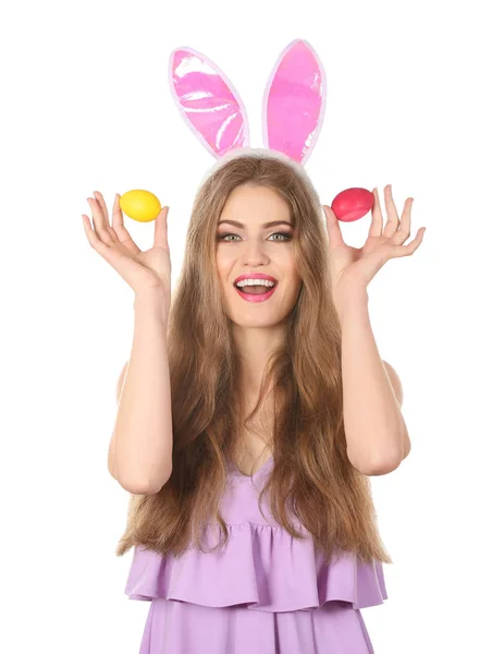 Beautiful young woman with Easter eggs and bunny ears on white background — Stock Photo, Image