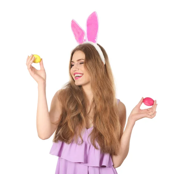 Красивая молодая женщина с пасхальными яйцами и кроличьими ушами на белом фоне — стоковое фото