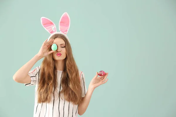 Paskalya yumurtaları ve tavşan kulakları renk arka plan üzerinde olan güzel kadın — Stok fotoğraf