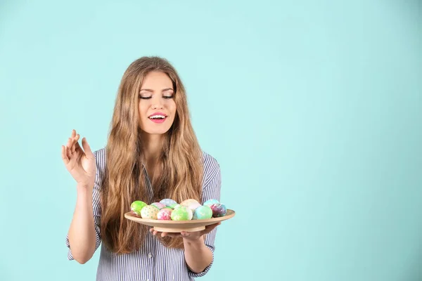 Beautiful young woman with painted Easter eggs on color background — Stock Photo, Image