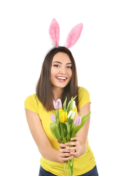 Mooie jonge vrouw met Easter bunny oren en boeket bloemen op witte achtergrond — Stockfoto