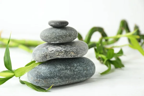 Spa stones and bamboo branch on white table — Stock Photo, Image