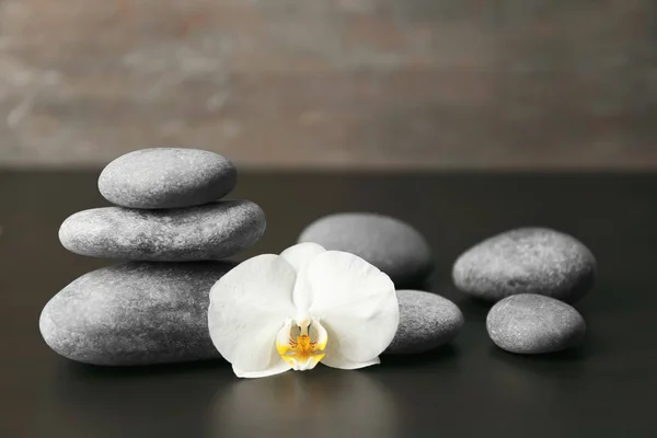 Spa taşlar ve karanlık masada güzel orkide çiçek — Stok fotoğraf