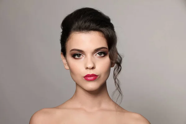 Portrait of young woman with beautiful professional makeup on grey background — Stock Photo, Image