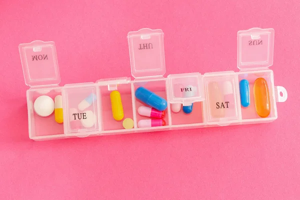 Recipiente de plástico com pílulas em fundo de cor — Fotografia de Stock