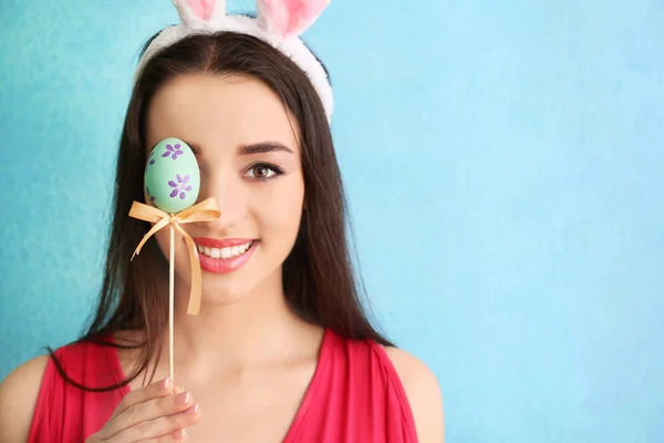 Beautiful young woman with Easter egg and bunny ears on color background — Stock Photo, Image