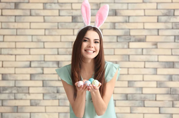 美丽的年轻女子与复活节彩蛋和兔子耳朵反对砖墙 — 图库照片