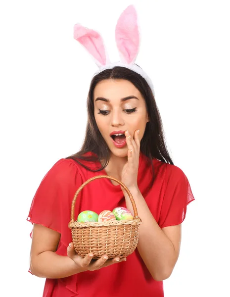 Emotional young woman with Easter eggs and bunny ears on white background — Stock Photo, Image