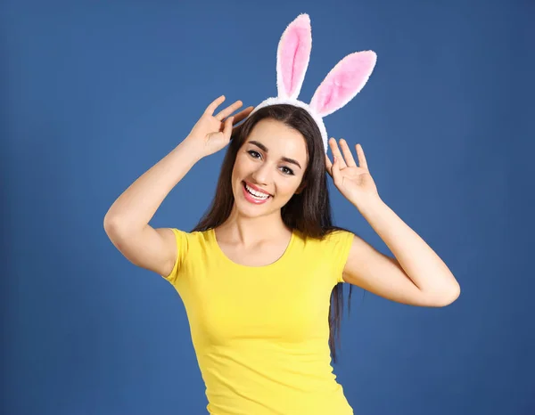 Mooie jonge vrouw met Easter bunny oren op kleur achtergrond — Stockfoto