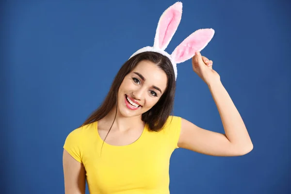 Belle jeune femme avec des oreilles de lapin de Pâques sur fond de couleur — Photo