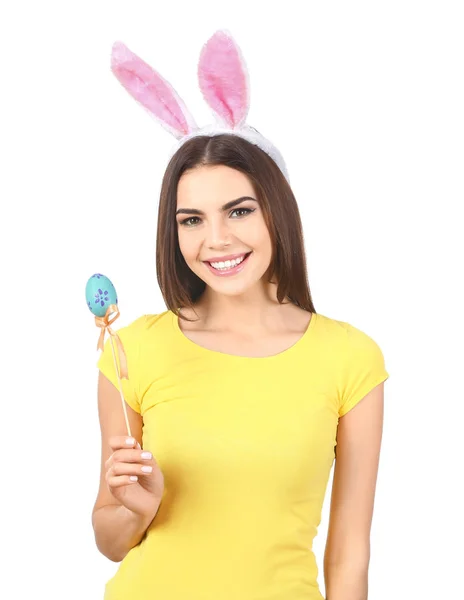 Красивая молодая женщина с пасхальным яйцом и кроличьими ушами на белом фоне — стоковое фото