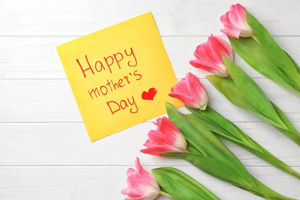 Красиві тюльпани і ручної карт для день матері на білому тлі дерев'яні, вид зверху — стокове фото