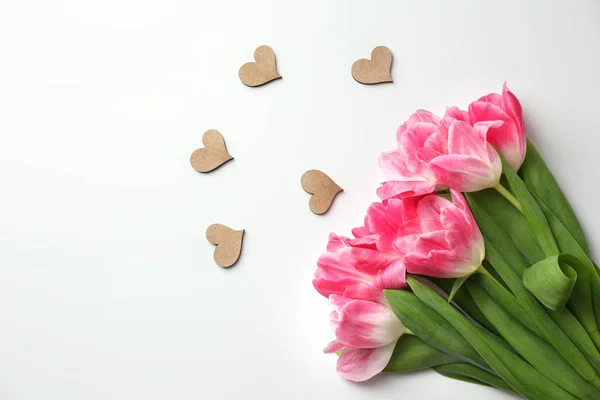 Prachtige tulpen en kleine decoratieve harten op witte achtergrond — Stockfoto