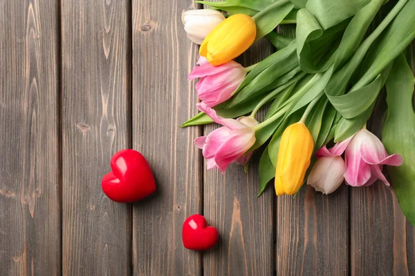 Piękne tulipany i dekoracyjne serca na tle drewnianych, widok z góry — Zdjęcie stockowe