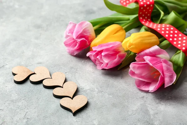 Hermosos tulipanes y corazones decorativos sobre fondo texturizado gris — Foto de Stock