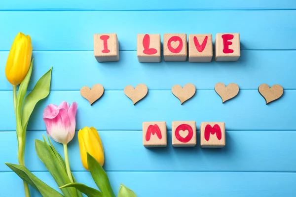 Bloques de madera con letras que forman frase I LOVE MOM y hermosas flores sobre fondo de color —  Fotos de Stock