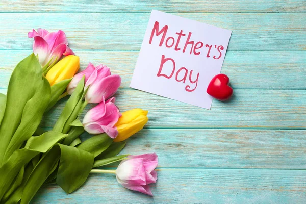 Piękne tulipany i ręcznie karty na dzień matki na podłoże drewniane — Zdjęcie stockowe