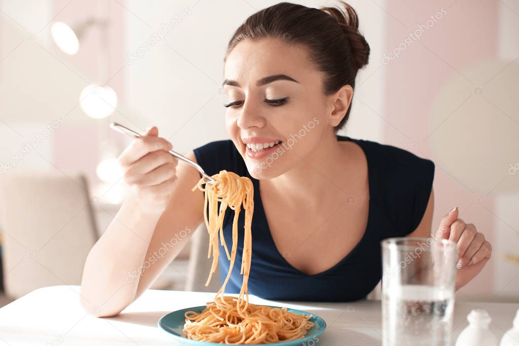 Young woman eating tasty pasta in cafe