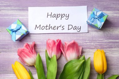 Güzel lale, tebrik kartı ve ahşap arka plan üzerinde anneler günü için hediye