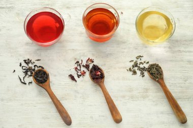 Kaşık kuru çay yaprakları çeşitli ve ahşap arka plan aromatik içkiler su bardağı ile