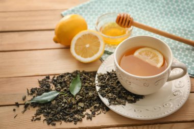 Bir ahşap masa üzerinde limon aromalı içecek yeşil çay yaprakları ve kuru