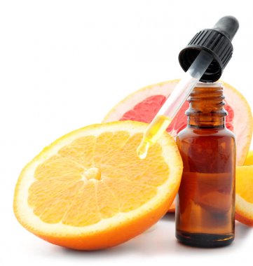 Damlalık ve beyaz zemin üzerine dilimlenmiş meyve narenciye uçucu yağ şişe