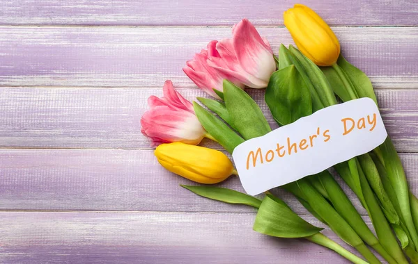 Piękne tulipany i ręcznie karty na dzień matki na podłoże drewniane, widok z góry — Zdjęcie stockowe
