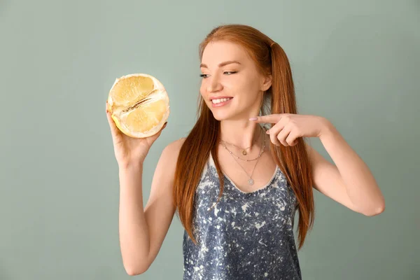 Beautiful young woman with citrus fruit on color background — Stock Photo, Image