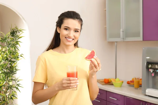 Mooie jonge vrouw met citrus fruit en een glas sap in keuken — Stockfoto