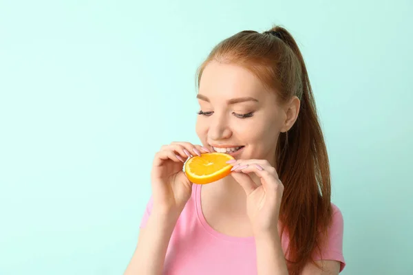Beautiful young woman eating citrus fruit on color background — Stock Photo, Image