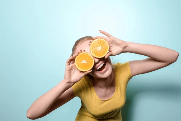 Funny young woman with citrus fruit on color background — Stock Photo, Image