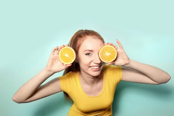 Funny young woman with citrus fruit on color background — Stock Photo, Image