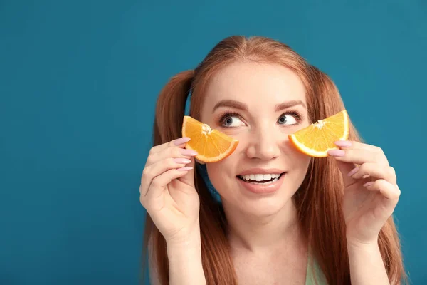 Funny young woman with slices of citrus fruit on color background — Stock Photo, Image