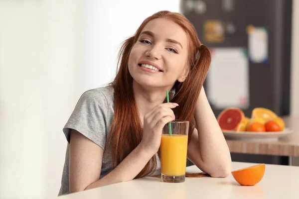 Mooie jonge vrouw drinken van SAP van citrusvruchten in keuken — Stockfoto